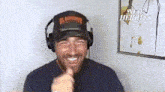 a man wearing headphones and a flamingo hat is smiling and pointing at the camera .