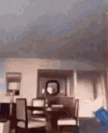 a blurry picture of a living room with a table , chairs , and a mirror .