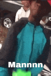 a man in a blue jacket is holding a green bottle and the word mannn is on the bottom of the screen .