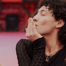 a man with curly hair is praying with his hands on his face