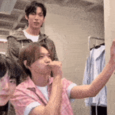 a man in a pink shirt is taking a picture of himself