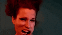 a woman with red hair is making a funny face with her mouth wide open .