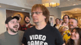 a man wearing a video games t-shirt stands in front of a group of people