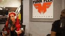 a woman with red hair is talking into a microphone while a man watches .