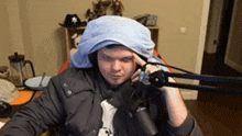 a man wearing a towel on his head is sitting in front of a microphone .