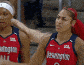 a woman in a washington jersey stands next to another woman in a car max jersey