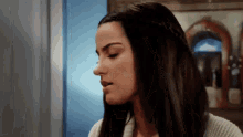 a woman with long dark hair is wearing a white sweater and braided hair .