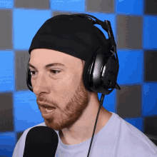 a man with a beard wearing headphones and a black hat
