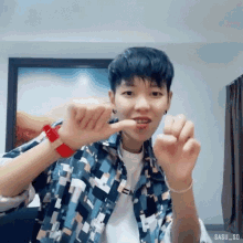 a person wearing a colorful shirt and a red watch is making a heart shape with their fingers