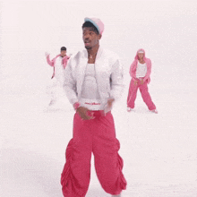 a man in a white jacket and pink pants is dancing with two other people