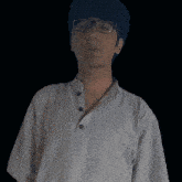 a man wearing glasses and a hat is standing in front of a dark background