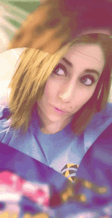 a woman wearing a blue shirt with a yellow circle on it looks at the camera