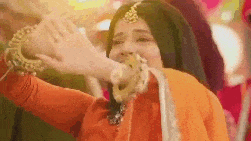 a woman in a red dress is holding a gold ring in her mouth .