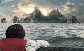 a man in a life jacket is looking out over the ocean at mountains