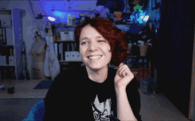 a woman wearing a black shirt with a leaf on it smiles