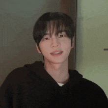 a young man wearing a black hoodie looks at the camera