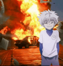 a boy in a white shirt with the number 99 on it is standing in front of a car that is on fire .