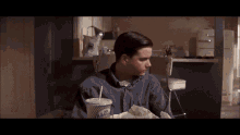 a man is sitting at a table with a drink and a sandwich
