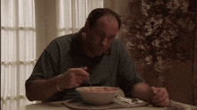 a man sits at a table eating a bowl of soup