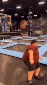 a man in a red shirt is jumping on a trampoline