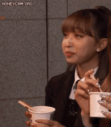 a woman in a suit is holding a cup of ice cream with a heart on it .