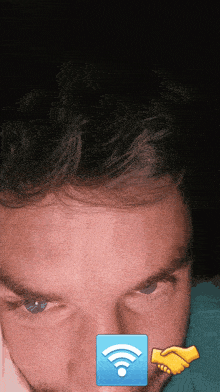 a close up of a man 's face with a blue square with a wireless symbol on it