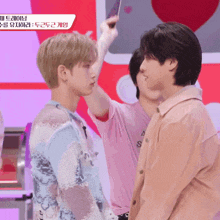 a man in a pink shirt with the letter s on it is standing next to another man
