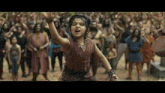 a little girl is dancing in front of a crowd of people in a movie .