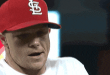 a man wearing a red cardinals hat looks to his left