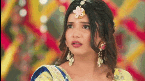 a woman wearing a yellow dress and earrings is looking at the camera .