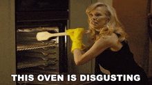 a woman wearing yellow gloves is holding a wooden spoon in front of an oven that says " this oven is disgusting "