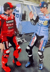 two motorcycle racers wearing lenovo and ducati uniforms are dancing together