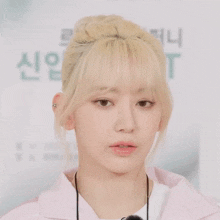 a woman with blonde hair is wearing a pink shirt and a lanyard around her neck