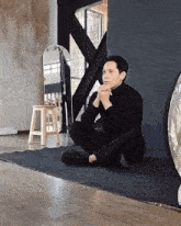 a man in a black turtleneck sits on the floor