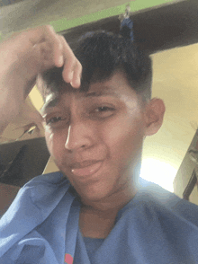 a young man in a blue scrub top is making a funny face