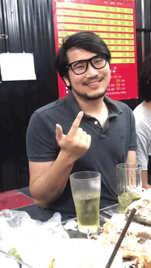 a man giving the middle finger while sitting at a table with food