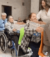 a group of elderly women in wheelchairs holding boxes in a room .