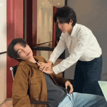a man in a white shirt is touching another man 's neck