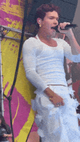a man singing into a microphone while wearing a white shirt and white pants