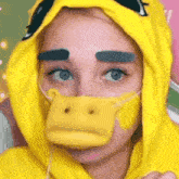 a woman in a yellow duck costume is wearing a yellow duck mask .