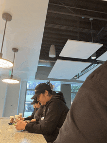 a man wearing a black hat with the word vans on it sits at a counter in a restaurant