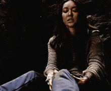 a woman is holding a man 's hand in a dark room and looking up .
