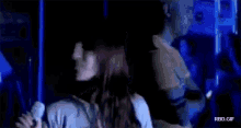 a woman is dancing in a dark room while a man looks on .