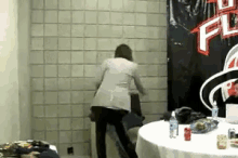 a woman is standing in front of a wall with a banner that says ' wwe ' on it .