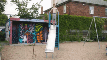 a man stands on top of a slide in front of a mural that says " purple "
