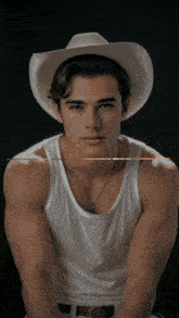 a young man wearing a cowboy hat and a tank top