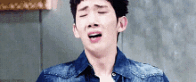 a young man in a denim jacket is crying with his mouth open .