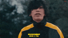 a young man wearing a black and yellow jacket is standing in front of a car .