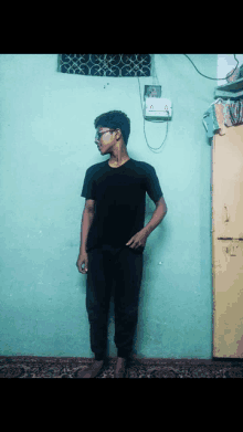 a young man standing in front of a green wall