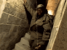 a man in a hat is standing in a narrow tunnel